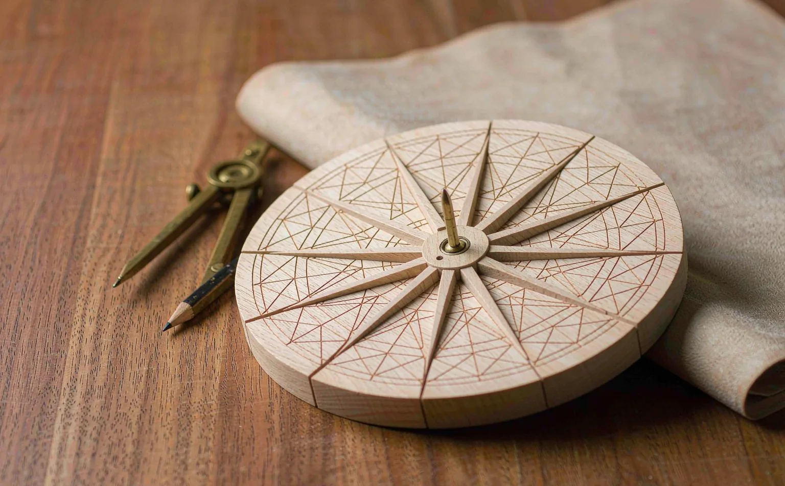 Ruota astrologica in legno divisa in dodici settori uguali, con un compasso di ottone accanto